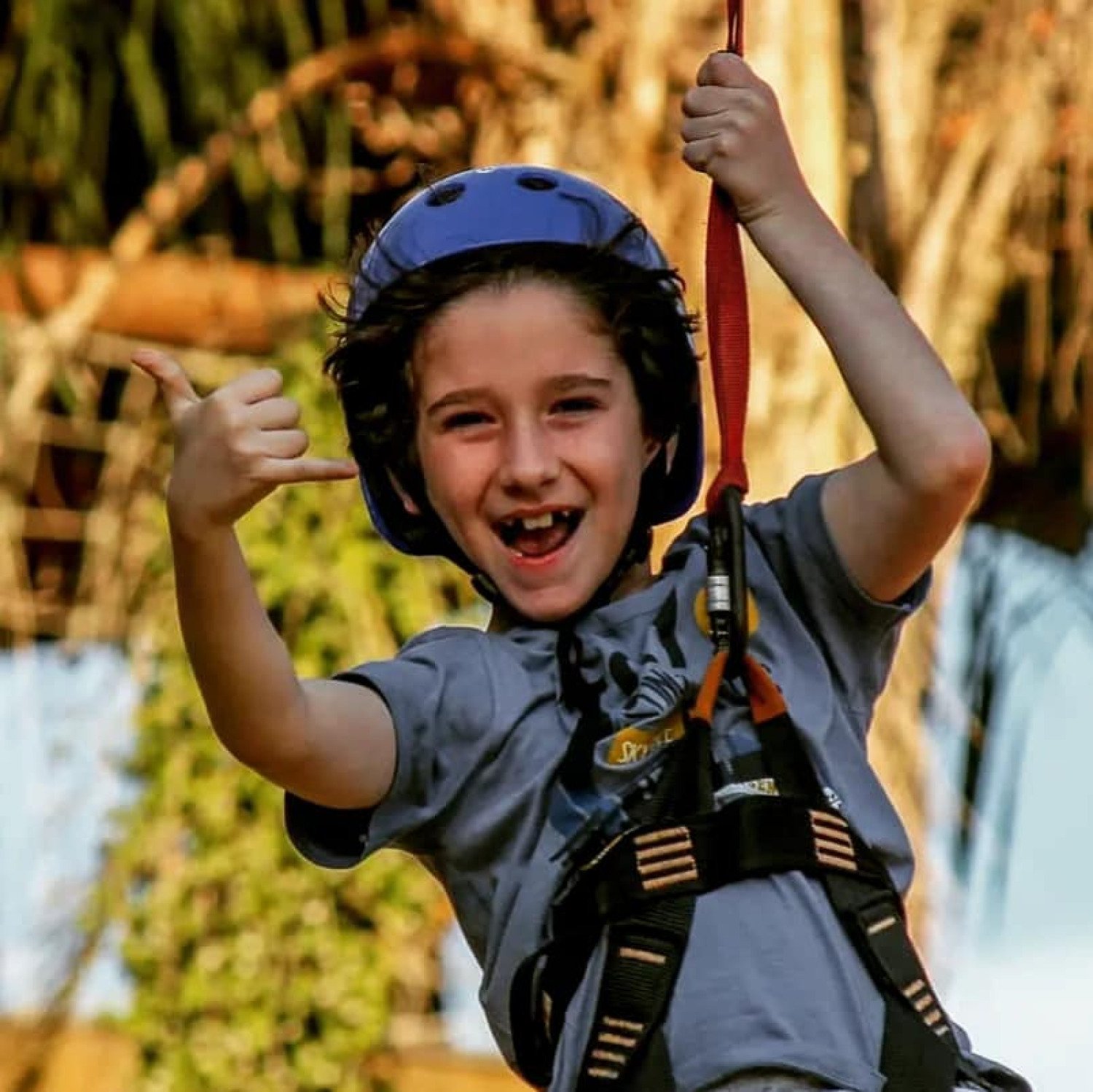 Criança sorrindo durante a experiência de tirolesa